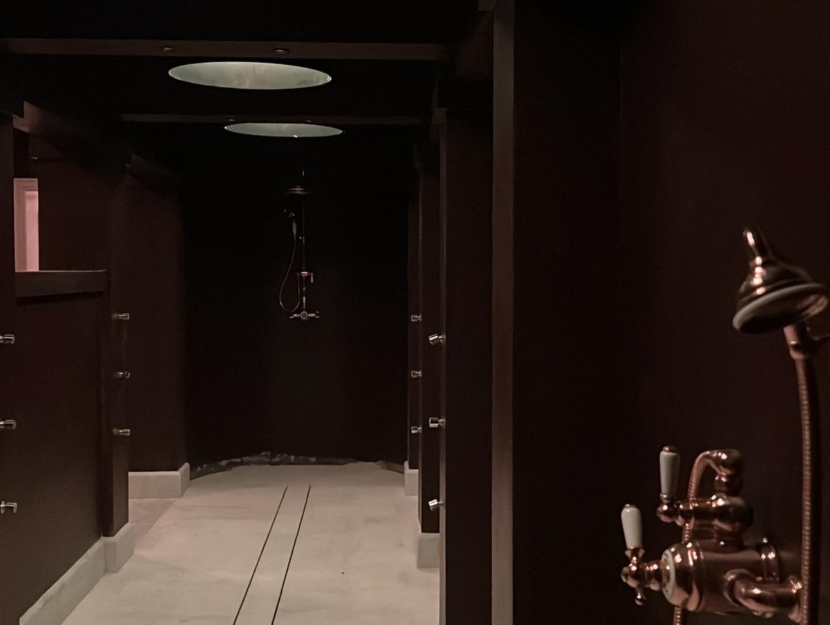 Eynsham Hall shower corridor with dark panelled walls and a pale seamless floor