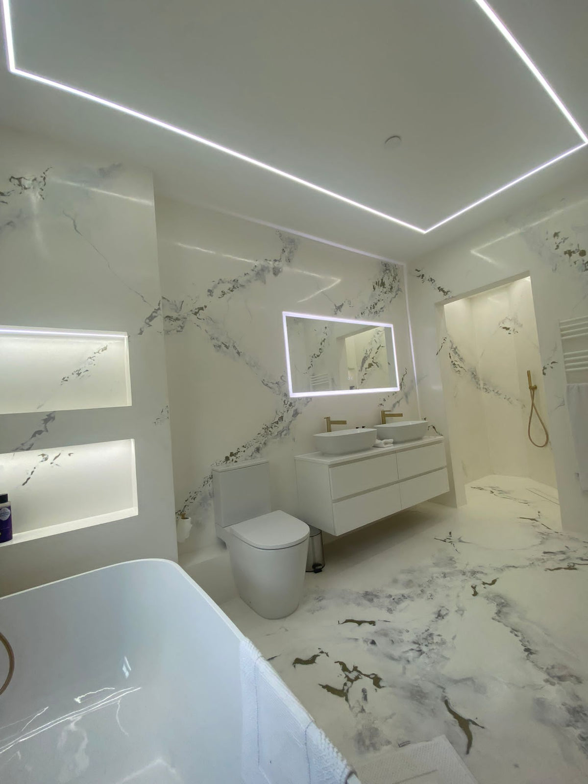Marble-effect bathroom with LED ceiling lighting and gold fittings