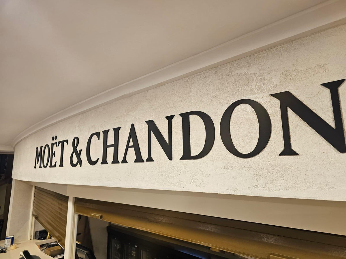 Moët & Chandon lettering on a textured white plaster bar fascia