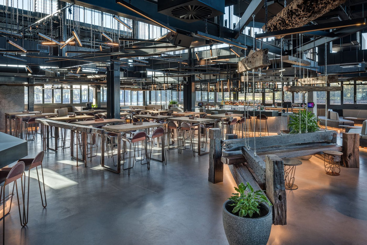 Large bar and restaurant with grey microcement floors and reclaimed timber