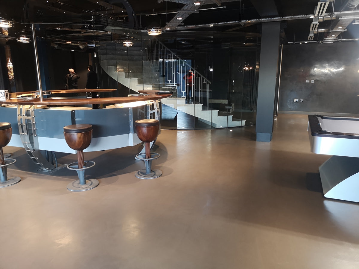 Bar and games room with a seamless bronze-grey microcement floor