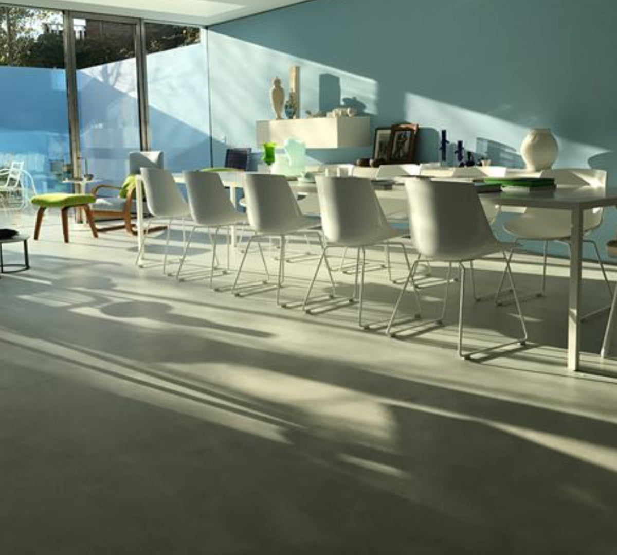 Sunlit dining area with a seamless pale grey microcement floor