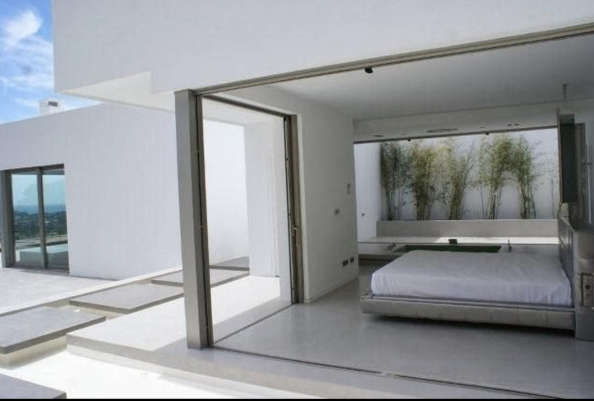 Minimalist white villa bedroom opening onto a terrace with seamless white floors