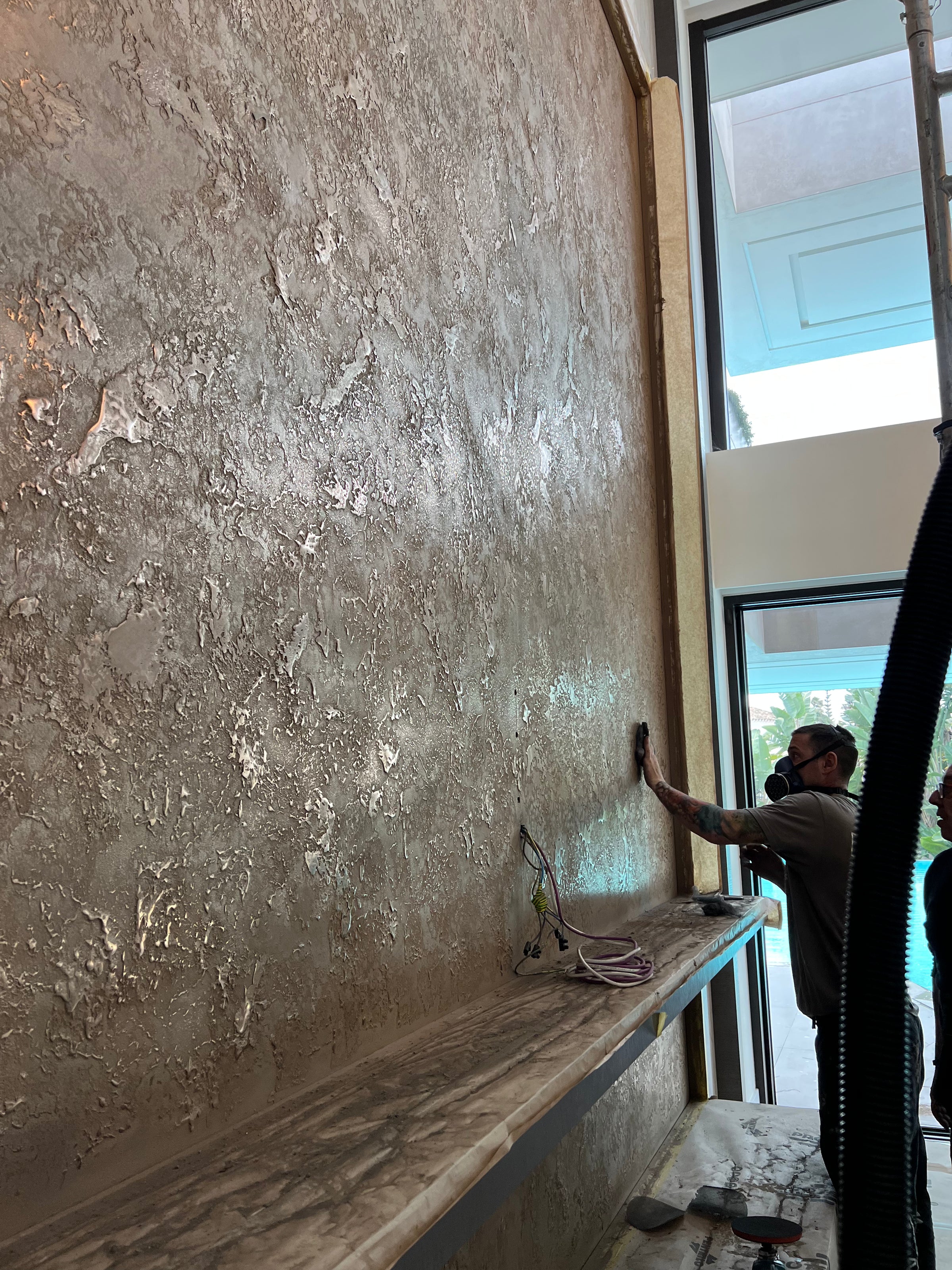 Applicator working on a double-height bronze metallic feature wall