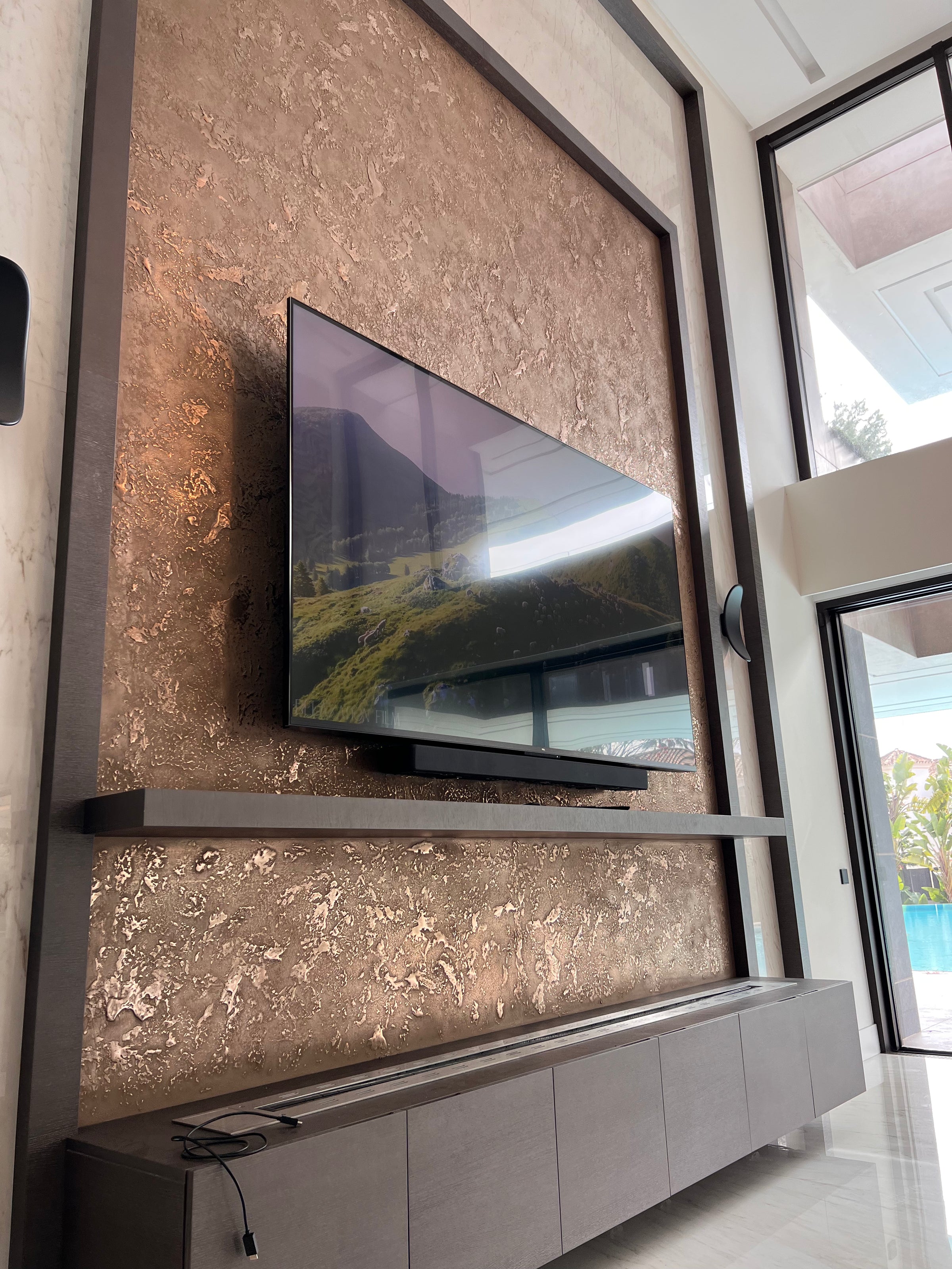 Bronze metallic textured feature wall behind a wall-mounted TV