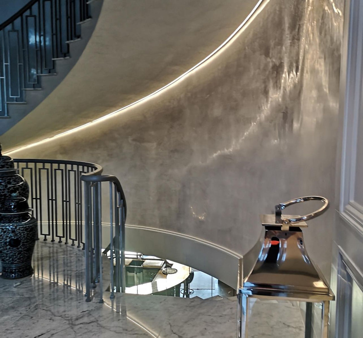 Curved staircase wall in silver Venetian polished plaster with LED lighting