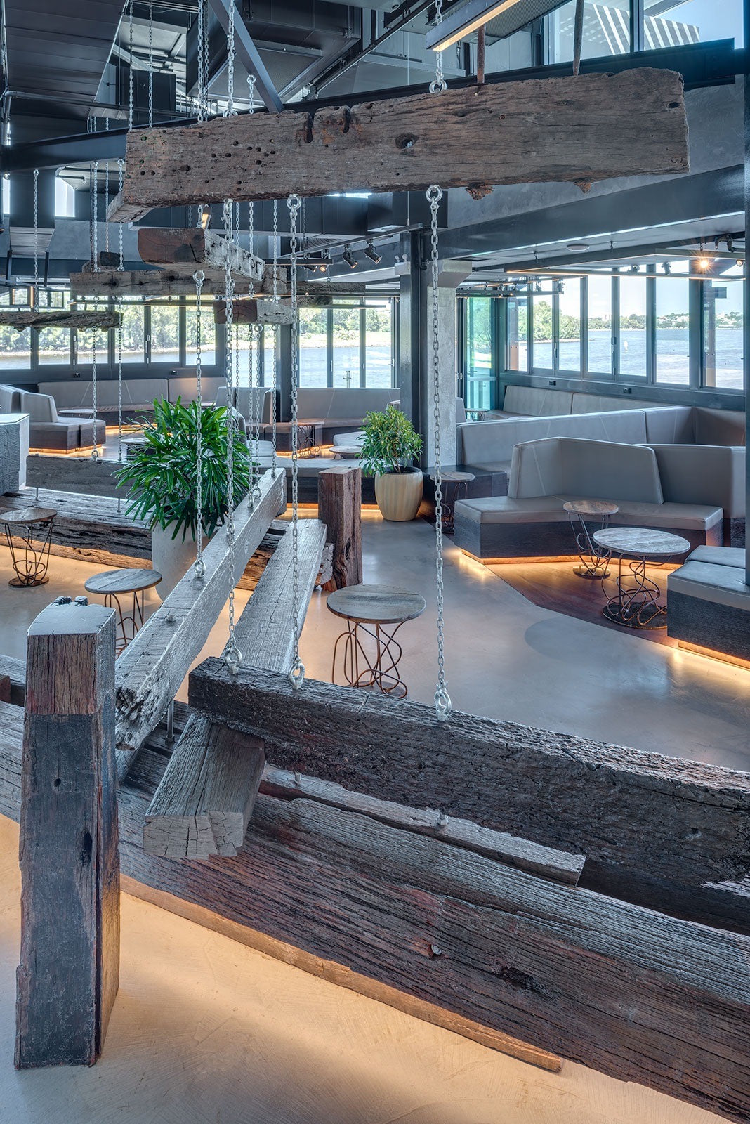 Waterfront bar with grey microcement floors and reclaimed timber features