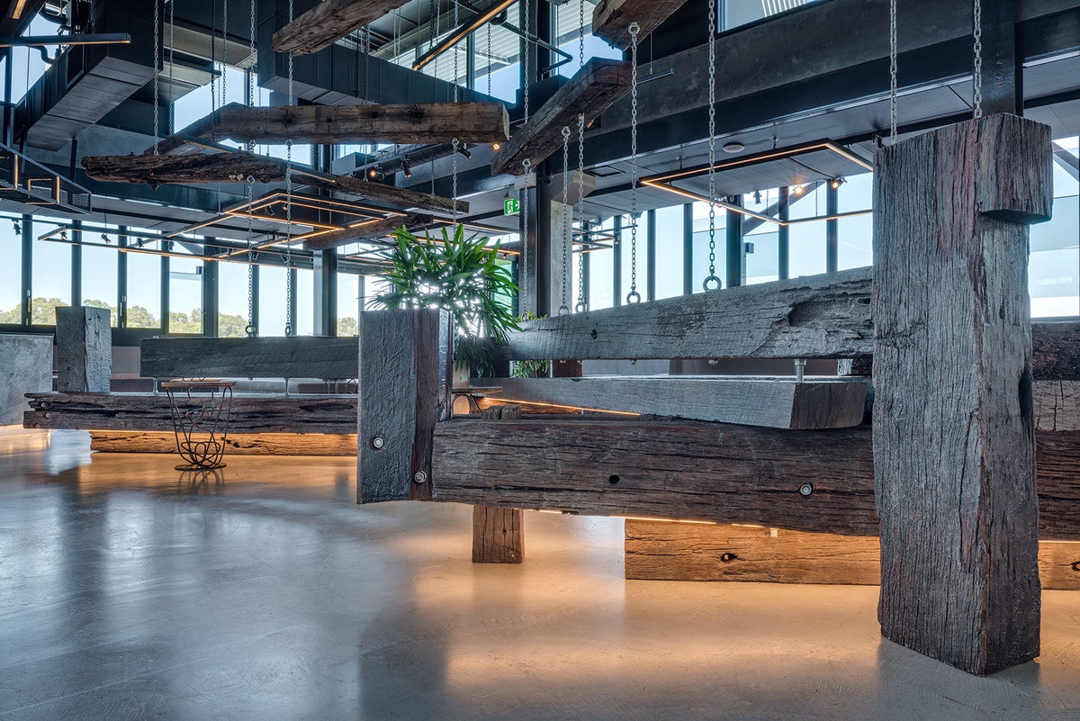 Ku De Ta bar with a polished grey microcement floor and suspended timber beams