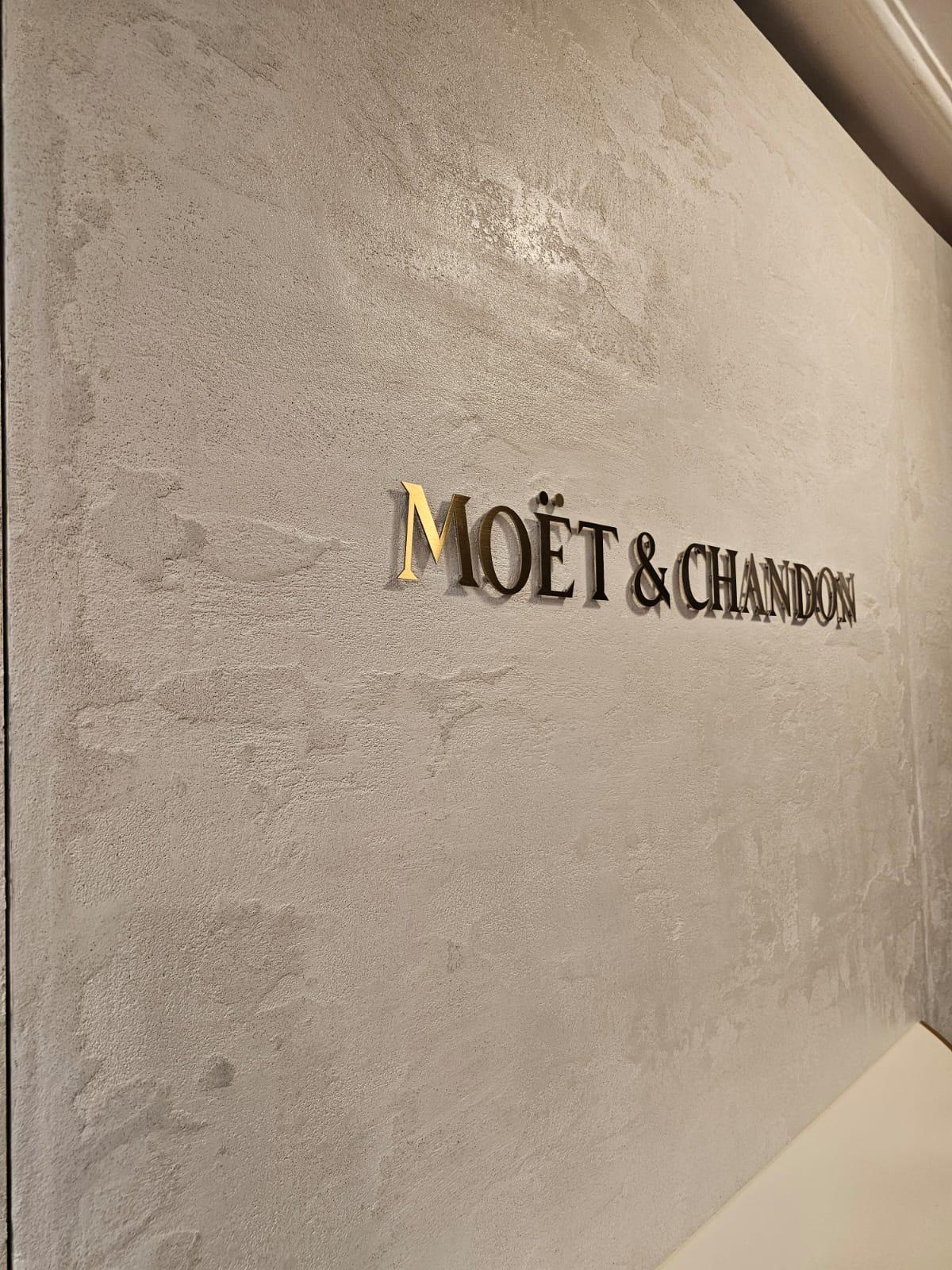 Moët & Chandon logo on a grey polished plaster wall