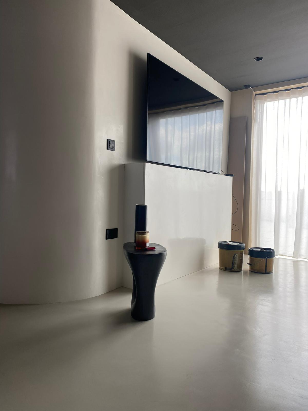 Living area with curved white microcement walls and a seamless floor