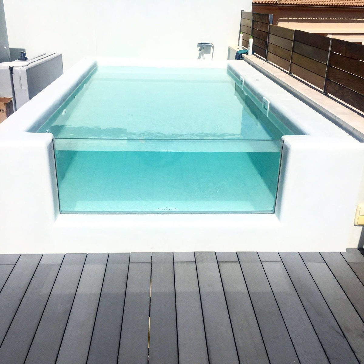 Raised glass-sided pool with microcement interior on a timber deck