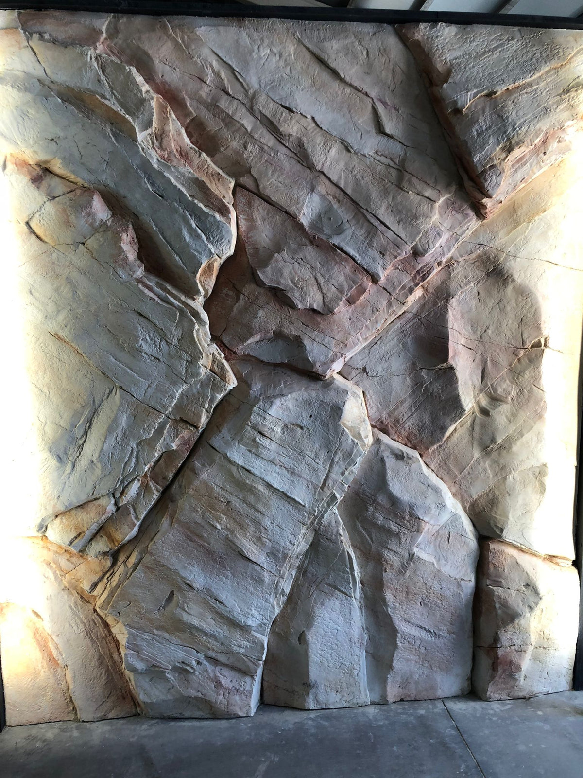 Pale sandstone-effect rock wall with pink and ochre veining