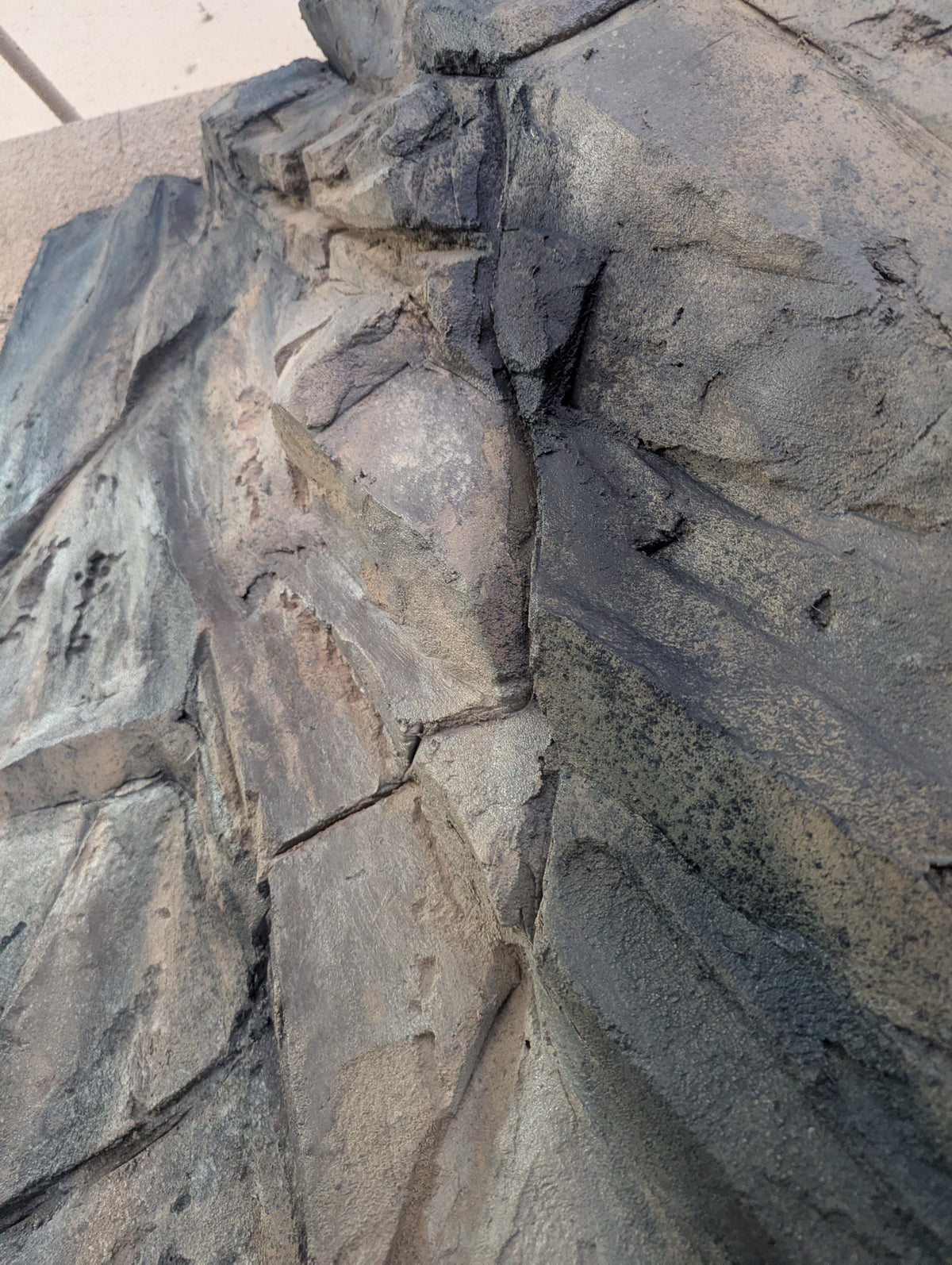 Close-up of carved grey faux rock with sandy tones