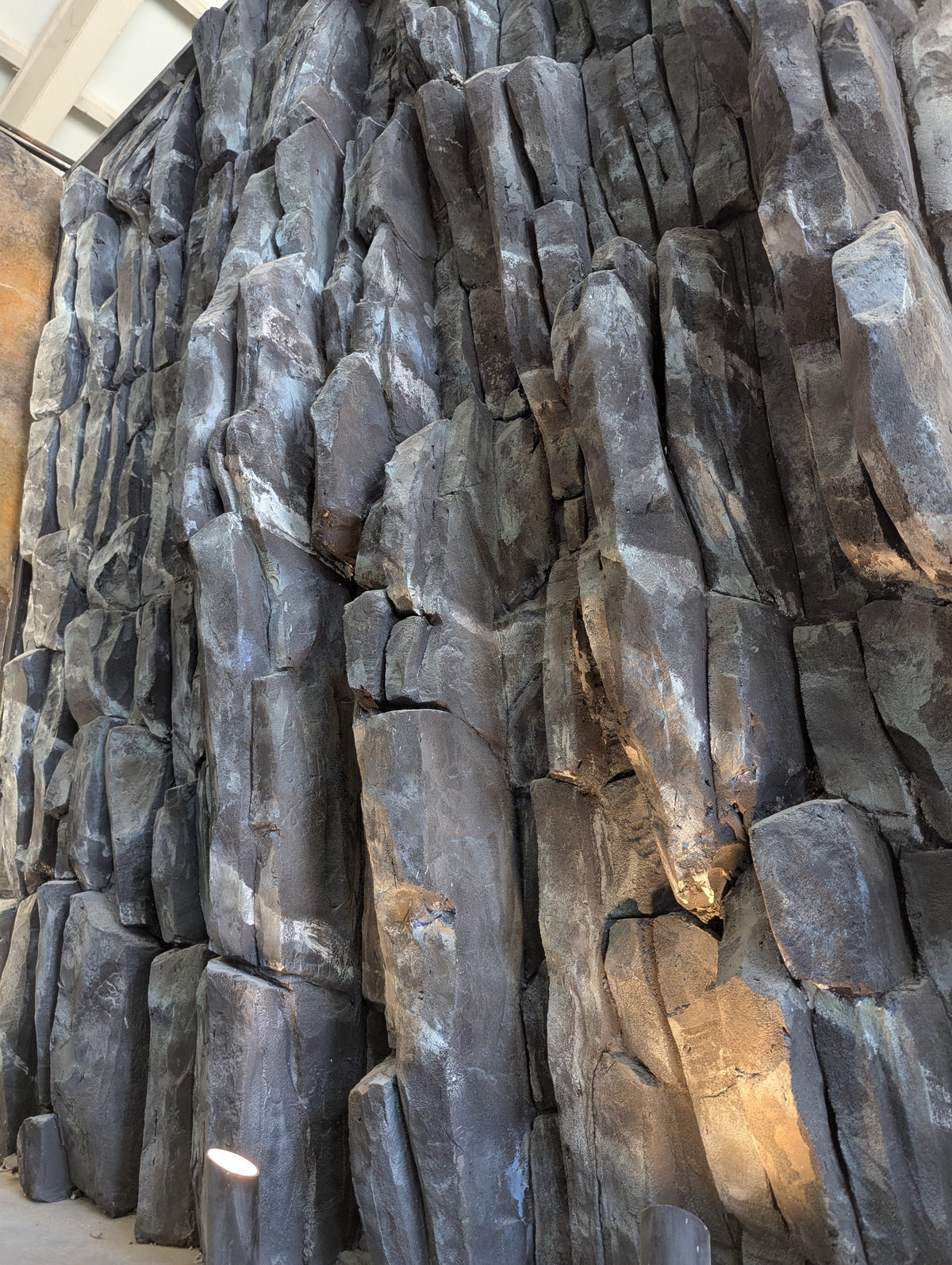 Dark basalt column-effect rock wall with uplighting